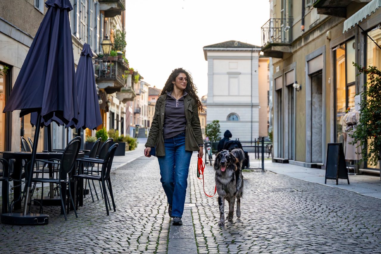 Mensch geht mit Hund an der Leine durch eine Altstadtgasse
